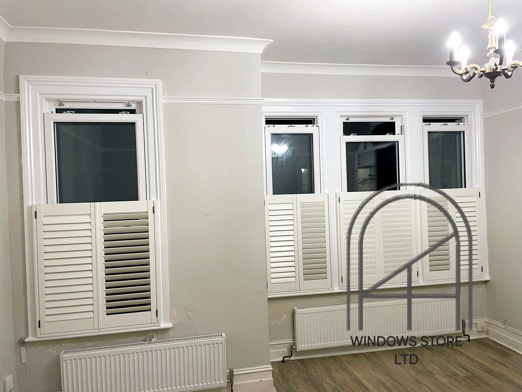 White full-height shutters framing a living room window, London
